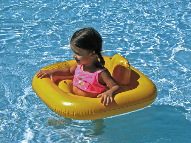 dítě v plovacím kruhu plave v bazénu